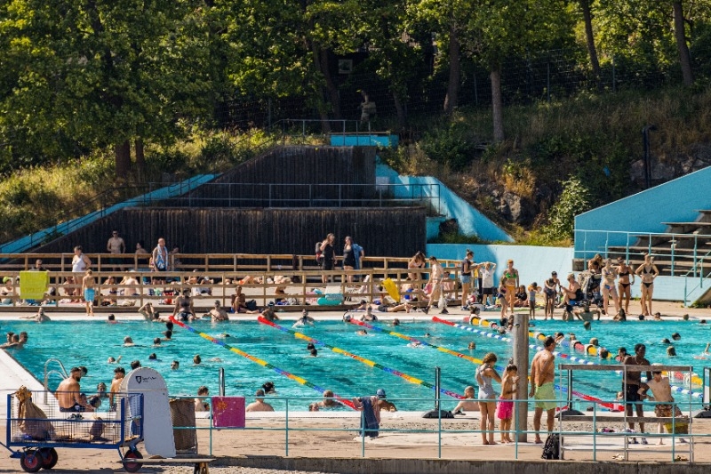 A lot of people at a public swimming pool.